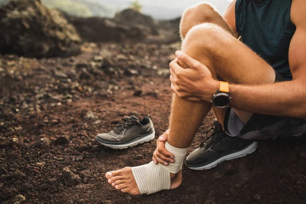 Man bandaging injured ankle. Injury leg while running outdoors. — Stock Photo, Image