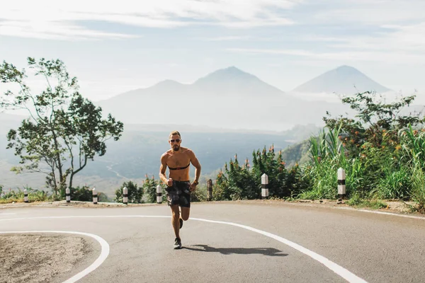 Человек бежит топлесс в гору по асфальтовой дороге в жаркое лето — стоковое фото