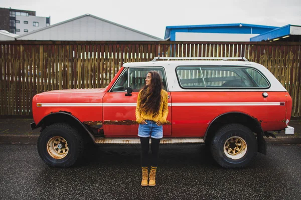 Young happy woman in orange sweater and jeans short near old ret — Stock Photo, Image