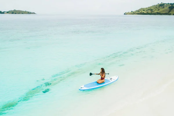 Mujer remando en sup board y disfrutando de turquesa transparente w — Foto de Stock