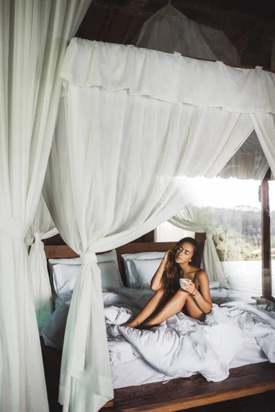 Slim tan woman waking up and enjoyning morning coffee in traditi — Stock Photo, Image