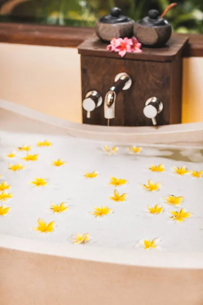 Bathtub with foam bubbles and yellow flowers close-up — Stock Photo, Image