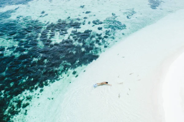 Mujer buceando con muchos tiburones pequeños cerca de la playa de arena blanca en — Foto de Stock