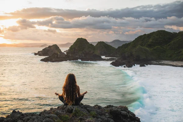 Giovane donna che pratica yoga in posa loto al tramonto con beautif — Foto Stock