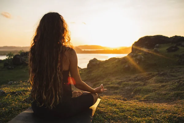 Woman meditating yoga alone at sunrise mountains. View from behi — Stock Photo, Image