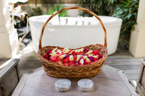 Wooden wicker basket with red and white flower petals in front o — Stock Photo, Image
