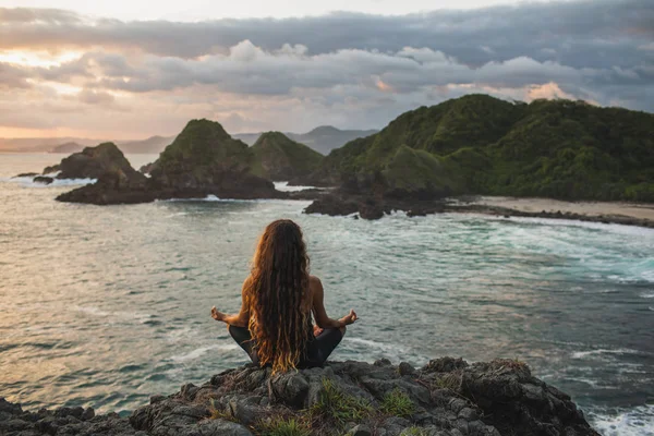 Молода жінка практикує йогу в позі лотоса на заході сонця з красивим — стокове фото