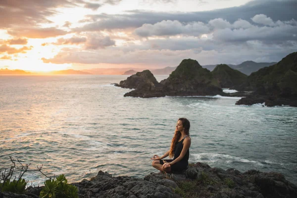 Молода жінка практикує йогу в позі лотоса на заході сонця з красивим — стокове фото