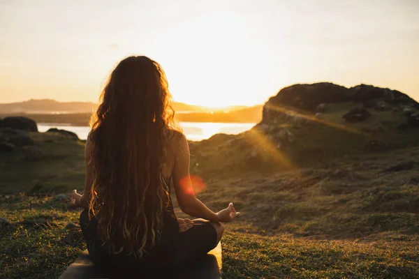 Woman meditating yoga alone at sunrise mountains. View from behi — Stock Photo, Image