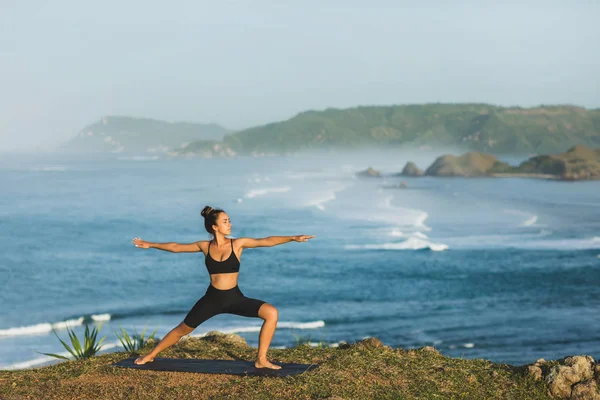Žena s úžasným oceánem a horami v přírodě trénuje. — Stock fotografie