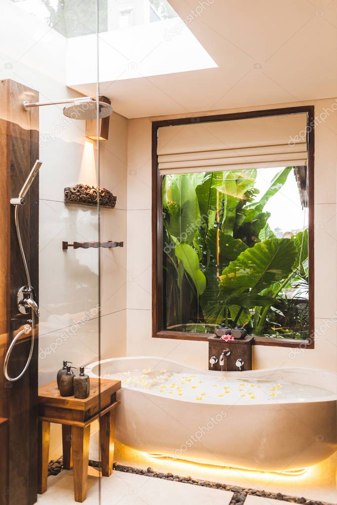 Modern interior of bathroom with bathtub and tropical garden vie