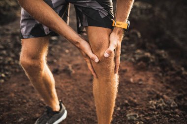 Dışarıda koşarken diz sakatlığı. Elleri yakın diz tutan adam