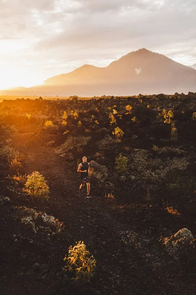 Trilha jovem atleta do sexo masculino correndo nas montanhas ao nascer do sol. Amazina — Fotografia de Stock