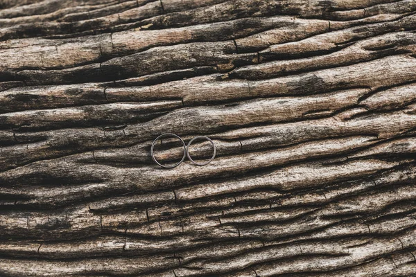 Dois anéis de casamento em fundo de textura marrom de madeira perto — Fotografia de Stock