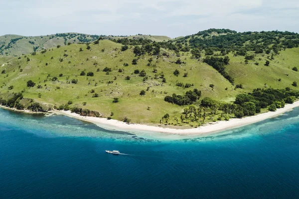 Inselküste mit grünen Hügeln, weißem Strand und Boot auf klarem Wasser — Stockfoto