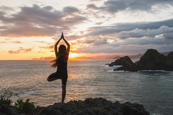 Joven mujer delgada practicando yoga al atardecer con hermoso océano —  Fotos de Stock