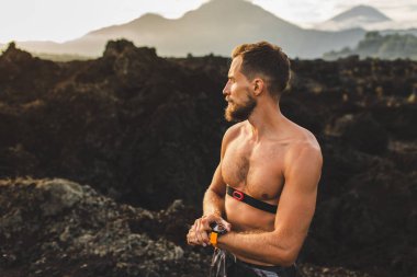 Atletik adam akıllı saat veya fitness izci programı çalışan başlar. Eğitim üstsüz ve göğüs kalp hızı monitörü kullanarak. Açık havada çalışan patika.