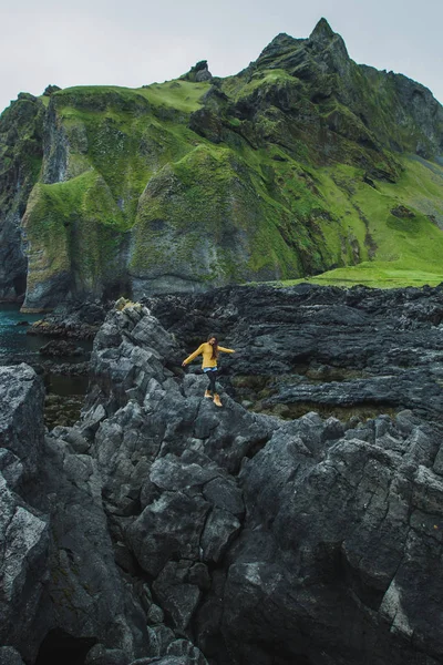 Жінка, проходячи чорним каменем скелясті вулканічна берегова лінія Вестман — стокове фото