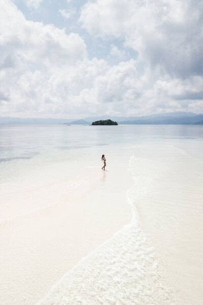 Woman walking alone on amazing tropical white sand beach. Aerial