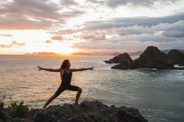 Joven mujer delgada practicando yoga al atardecer con hermoso océano —  Fotos de Stock