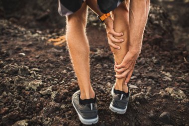 Male runner holding injured calf muscle and suffering with pain. clipart