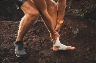 Male runner holding injured leg close-up and suffering with pain