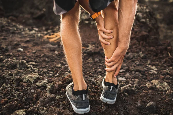 Male runner holding injured calf muscle and suffering with pain. — Stock Photo, Image
