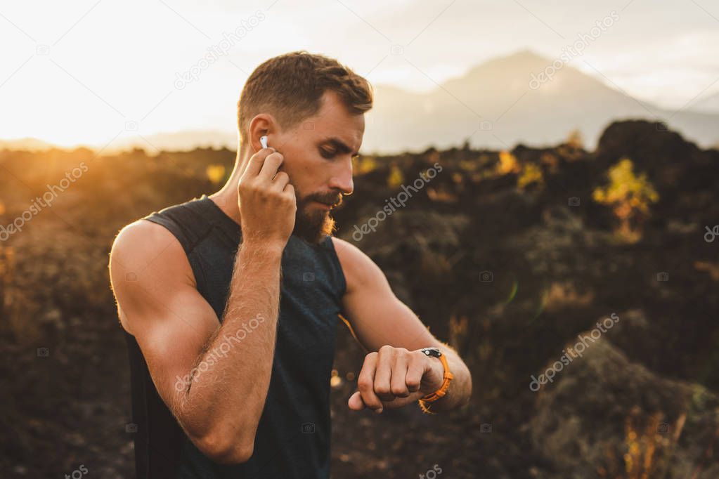 Male runner synchronizing wireless earphones with smart watch. P