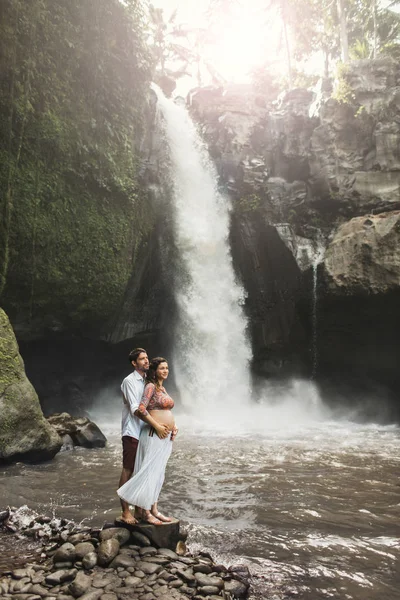 Joven pareja embarazada enamorada con increíble vista de Tegenungan c —  Fotos de Stock