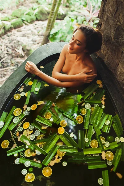 Bella giovane donna godendo in spa all'aperto. Bagno di pietra di lusso — Foto Stock