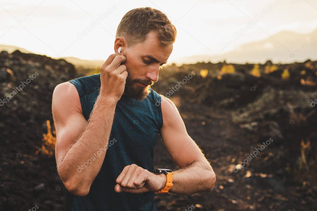 Male runner synchronizing wireless earphones with smart watch. P