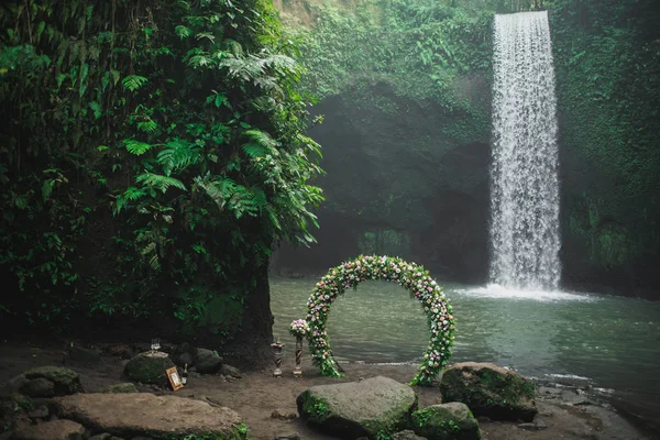 Wedding ceremony on Tibumana waterfall, Bali. Round arch with fr — Stock Photo, Image