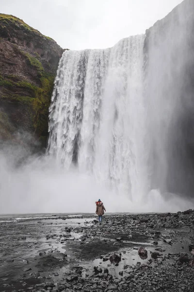 Mulher caminhando para Skogafoss Islândia famosa cachoeira. Poderoso st — Fotografia de Stock