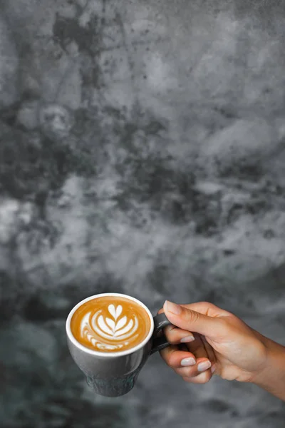 Woman holding in hand gray cup of fresh cappuccino on background — Stock Photo, Image