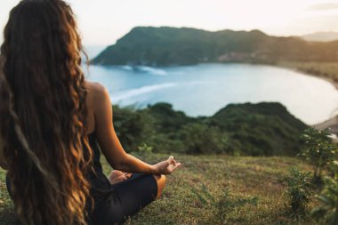 Güneş doğarken dağlarda tek başına yoga yapan bir kadın. Arkadan bak. Seyahat yaşam tarzı ruhsal rahatlama kavramı. Doğayla uyum..