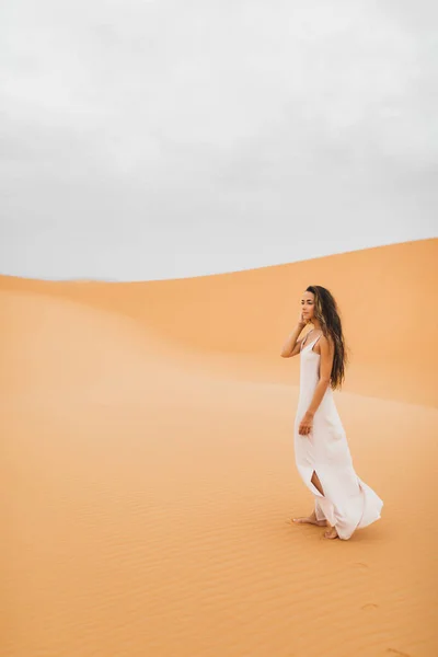 在摩洛哥撒哈拉沙漠的沙丘上 美丽的年轻美丽女子画像 留长发的布鲁内特型 东方型 穿白丝衣服的新娘 — 图库照片