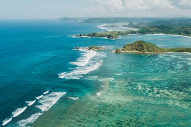 Lombok adasının kıyı şeridinin hava aracı görüntüsü. Tanjung Aan Körfezi. Okyanus dalgaları, berrak su ve mercan resifleriyle muhteşem bir manzara..