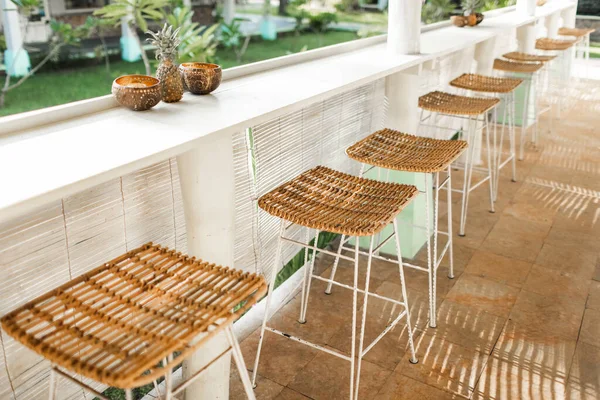 Wicker rattan chairs on bar counter. Trendy furniture design. Summer cafe terrace.