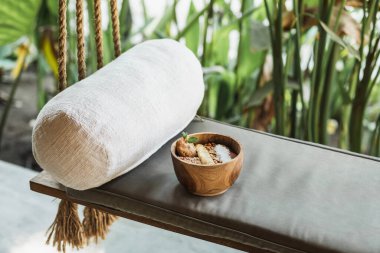 Salıncakta sallanan kanepede sağlıklı meyve püresi ve bahçede beyaz, rahat bir yastık olan ahşap bir kase. Vejetaryen yemeği. Modern kafe mobilya hipster tarzı..