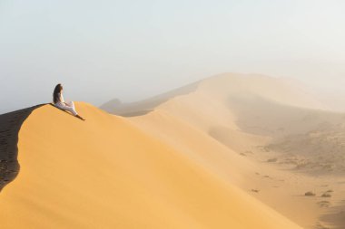 Rüya, yolculuk ve seyahat tutkusu konsepti. Mutlu kadın, Fas 'taki Sahra çölünün kumullarındaki fantastik gündoğumundan esinlenmiştir. Sabaha sisli ve ılık bir ışık.
