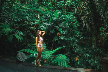 Güzel, ince esmer, beyaz mayo giymiş, kenar mahalle havuzu üzerinde, Jungle 'da. Bali.