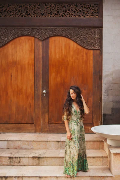 木製のドアの背景に緑の絹のドレスでブルネットの巻き女性の肖像画 アジア風 — ストック写真