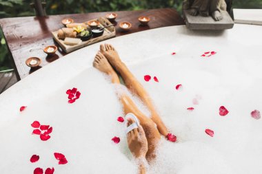 Bacaklarını köpükle yıkayan bir kadın ve doğal lif süngeri kullanıyor. Spa, vücut bakımı, romantik ruh hali..