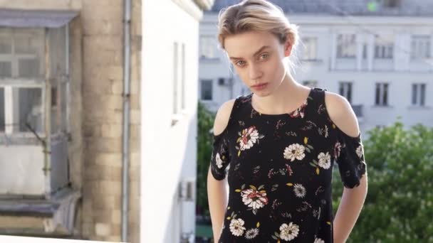Blond žena v šatech s květinami na pozadí ulice — Stock video