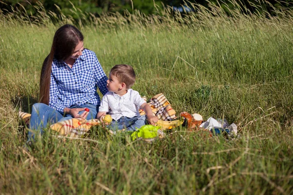 Mutter und Sohn essen bei einem Picknick auf einem Feld — Stockfoto