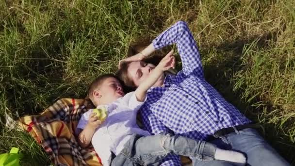 Mãe e menino em um piquenique sobre a natureza de comer — Vídeo de Stock