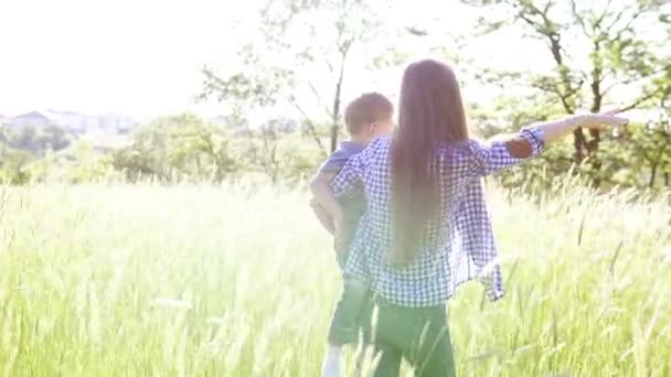 Vrouw met haar zoon in het hands van gaat over de aard van het veld — Stockvideo