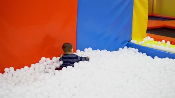 El niño jugando en el patio con pelotas — Vídeo de stock