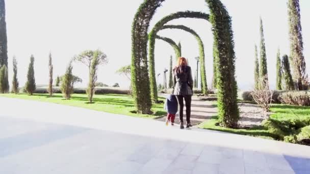 Мати і молодий син прогулюються парком — стокове відео