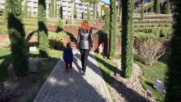 Moeder en jonge zoon lopen door het Park op straat — Stockvideo